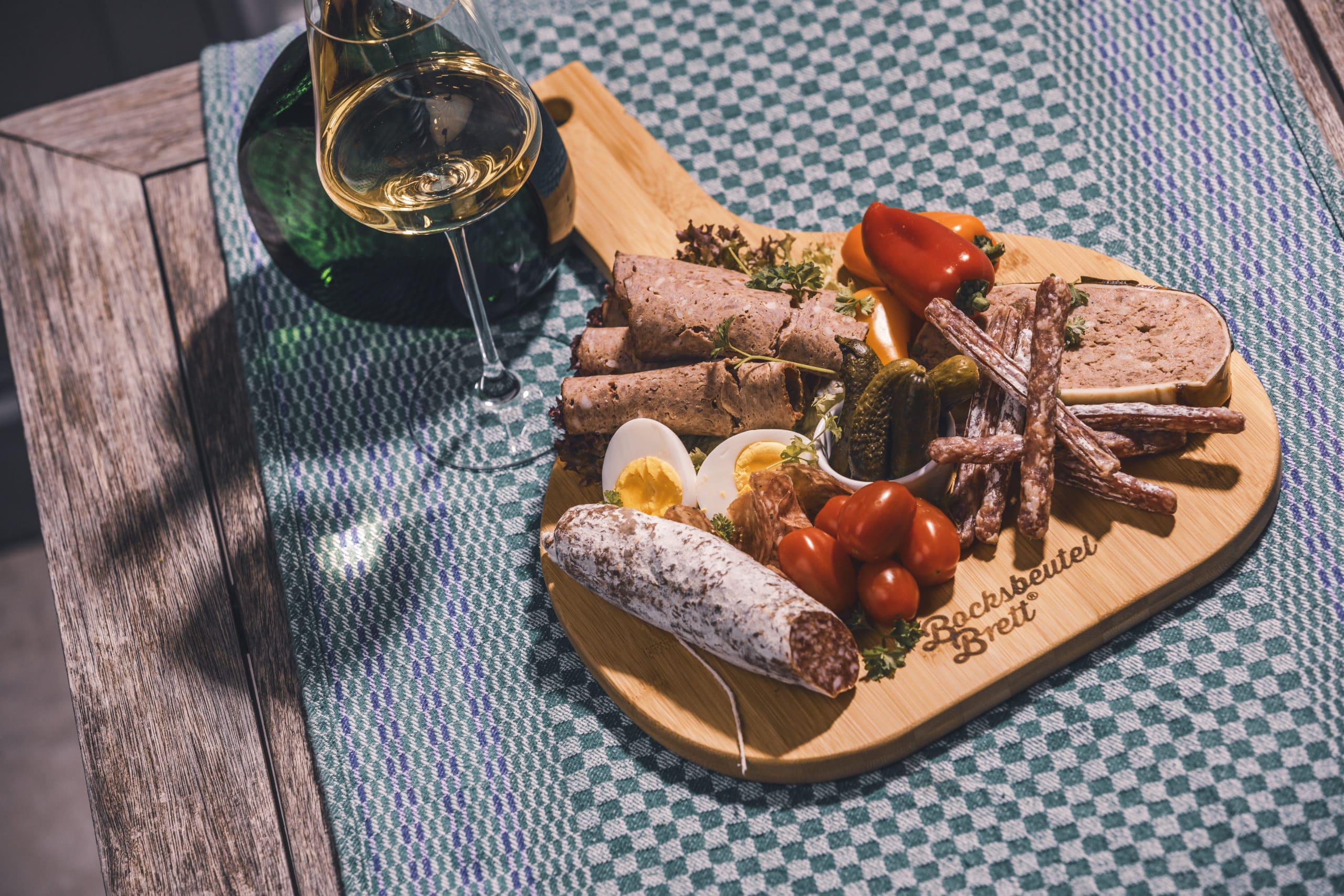 Eine fränkische Brotzeit mit Wurst und Wein serviert auf dem Bocksbeutelbrett.